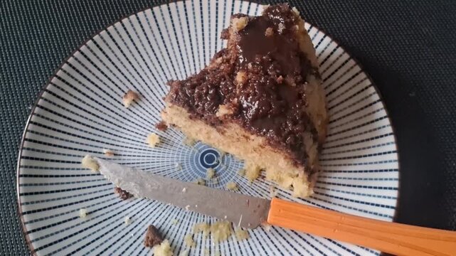Delicious slice of chocolate cake on a patterned plate with a knife beside the food