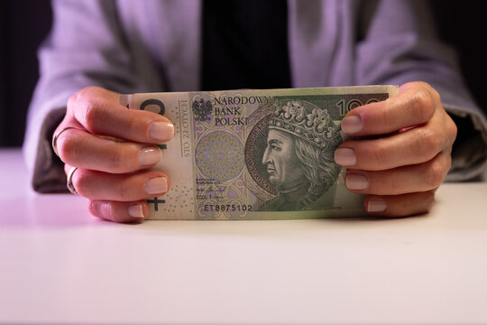 kobieta trzyma w dłoniach banknot 100 zł. Koncepcja płatności got&oacute;wką