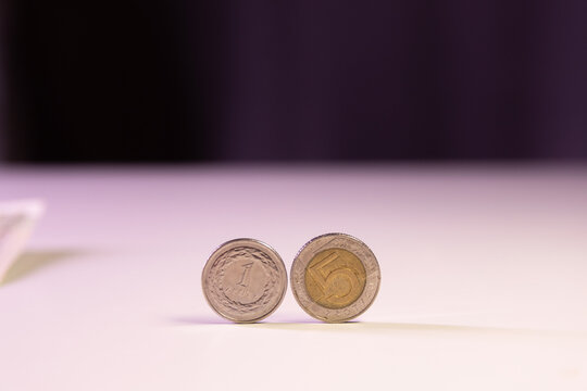 polskie monety toczą się po białym stole. symbol płatności got&oacute;wką
