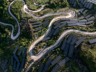 Obraz premium Aerial view of solar photovoltaic power station on mountain terrain with winding roads