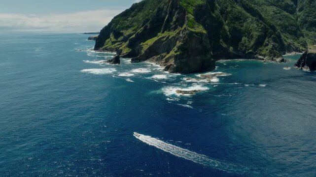 Cinematic Aerial Drone Shot of a Small Motorboat Speeding Through the Deep Blue Atlantic Ocean Along Dramatic Volcanic Cliffs, Flores Island