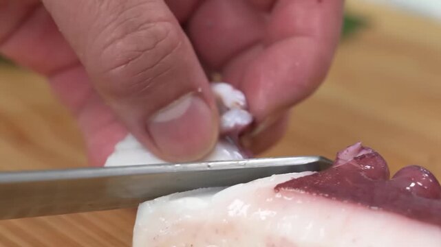 A professional chef uses expert knife skills to thinly slice a vibrant red radish on a wooden cutting board. The footage highlights precise culinary techniques used in Japanese cuisine or fine dining 