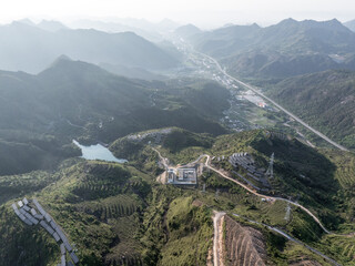 Fototapeta premium aerial view of mountain reservoir and power transmission facilities surrounded by green hills