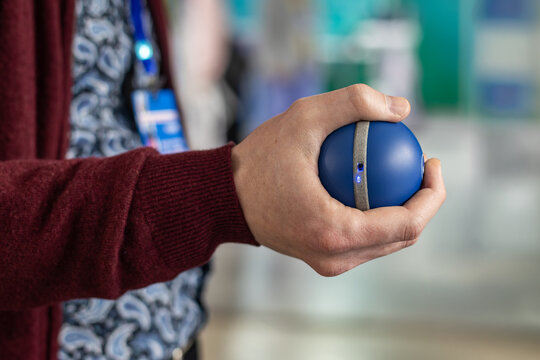 Hand holding blue therapy grip ball. Close up of a hand squeezing a blue therapy ball, showing grip strength training, rehabilitation, and hand exercise.