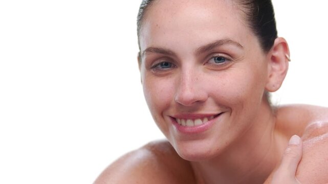 Beauty portrait of Latina with light complexion and freckles lifts head off her forearm on light background | nourished skin concept