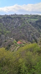 Fototapeta premium La magnifique chapelle auvergnate Notre-Dame d'Estours vue depuis les hauteurs avec les gorges de la Seuge juste derrière (Haute-Loire, Auvergne, France)