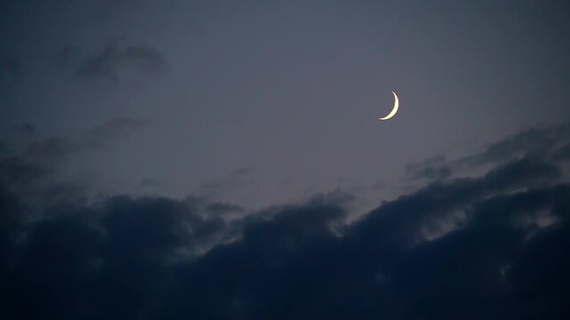 A partial moon and fast-moving clouds at dusk. Concepts of mysticism, esotericism, the supernatural, Halloween.