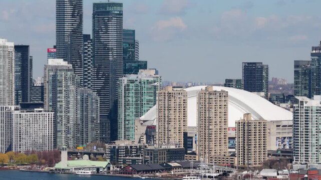 Toronto's modern skyline featuring the iconic Rogers Centre and contemporary high rise residential condominiums while commercial aircraft lands at the airport
