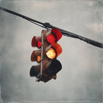 Close-up of illuminated yellow traffic light hanging on metal pole against cloudy sky