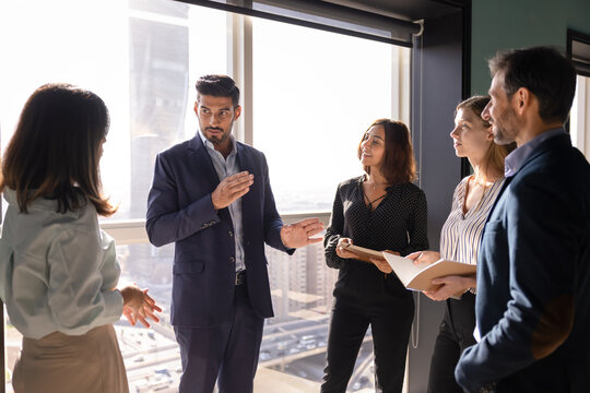 Diverse businesspeople discussing strategy in corporate office, listening team leader presents key points, explaining business ideas gathered for joint decision making, teamwork and project management