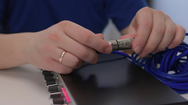 Sound technician connecting equipment. Detailed view of sound engineer attaching connector to device. Precise handling of audio cables during studio equipment setup and testing