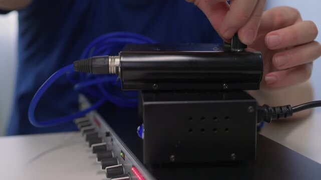 Sound technician connecting equipment. Detailed view of sound engineer attaching connector to device. Precise handling of audio cables during studio equipment setup and testing