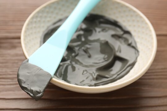 Mud therapy. Natural clay paste for facial and body care and brush on wooden table, closeup