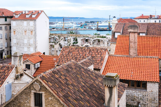 Aerial Split: Red roofs, ancient stone, busy port with ferries on the calm Adriatic