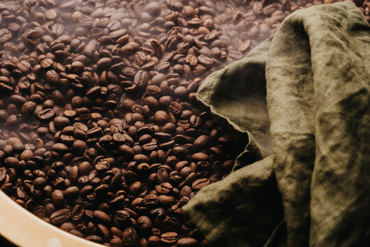 Granos de caf&eacute; reci&eacute;n tostados sobre charola dorada.