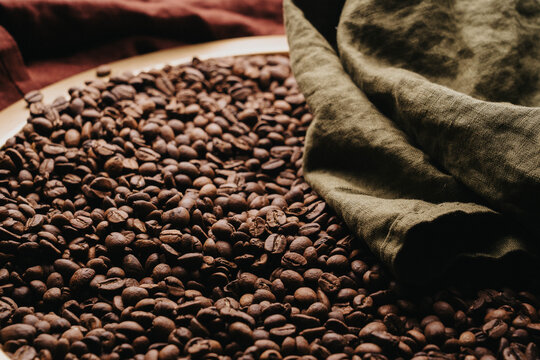 Granos de caf&eacute; reci&eacute;n tostados sobre charola dorada.