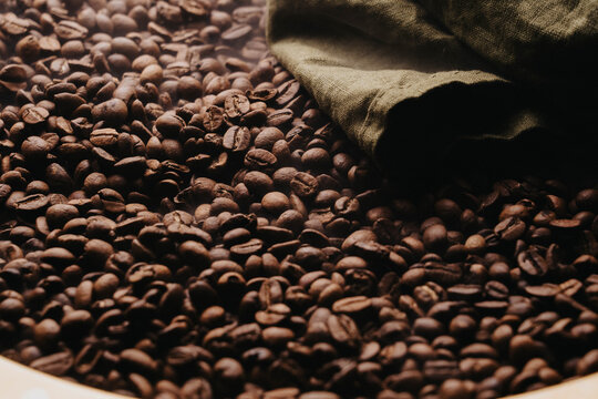 Granos de caf&eacute; reci&eacute;n tostados sobre charola dorada.