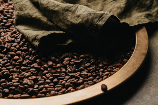Granos de caf&eacute; reci&eacute;n tostados sobre charola dorada.