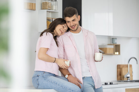 Young couple sharing morning coffee in modern kitchen, smiling and affectionate