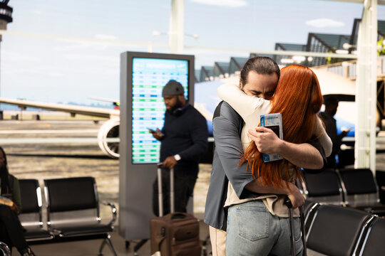 Couple meeting again in airport terminal after long-distance relationship, embracing with excitement and happiness. Emotional reunion at arrival gate, capturing authentic love and affection.