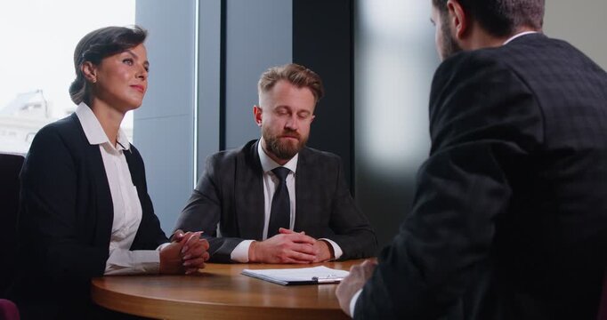 Professional manager explaining terms of contract to couple of business people. Clients listening to agent and reviewing document while exploring options before finalizing and signing agreement.