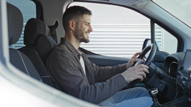 Young hispanic man smiling, giving thumbs up and hands on steering wheel inside a white van parked on street; confidence.