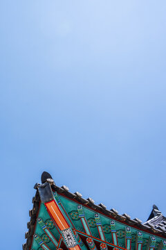 Beautiful color contrast between traditional dancheong patterns on wooden eaves and blue sky background