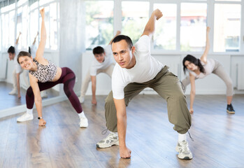 Fototapeta premium Young guys and girls in sportswear performing hip hop at group dance class