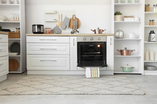 Interior of light kitchen with oven, pegboard and shelf units