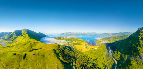 Fototapeta premium Drone view of a fjord in Leknes, Lofoten Islands, Norway. Panoramic aerial view of the northern summer. Scenic arctic landscape with high hills, ocean and northern nature. Background and wallpaper.