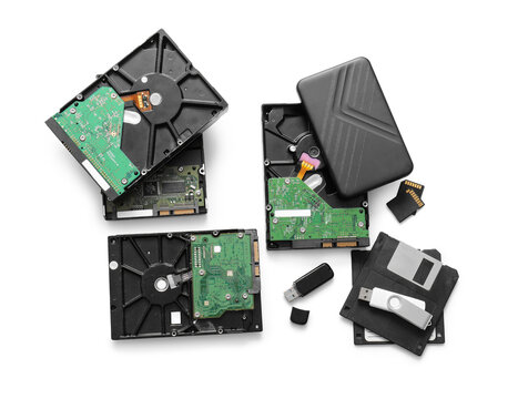 Different hard disk drives, USB sticks, SD cards and floppy disks on white background