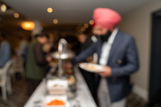 Blurred view of Sikh guests serving food during wedding reception.