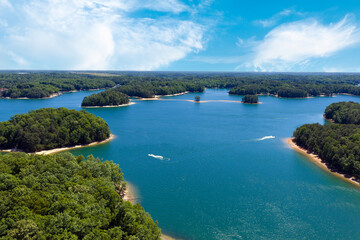 Obraz premium Lake Lanier in North Georgia, Aerial drone shot on a sunny day. Radiant clouds both blue and white. Clear view of trees and blue lake water