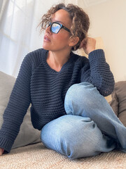 Obraz premium Woman in knit sweater and glasses relaxing at home, thoughtful casual portrait on couch