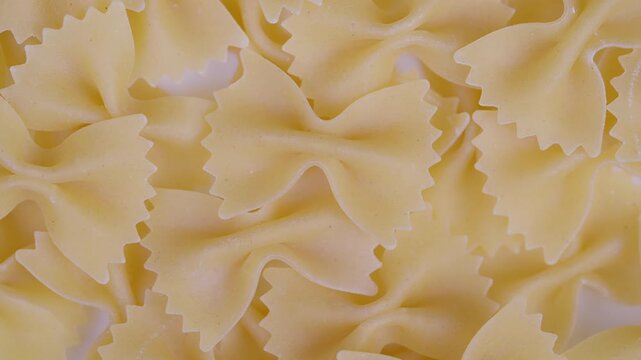 Magnified image of bow shaped noodles. Detailed macro photograph of pale bowtie pasta. Highresolution macro image capturing intricate features of uncooked bow shaped noodles