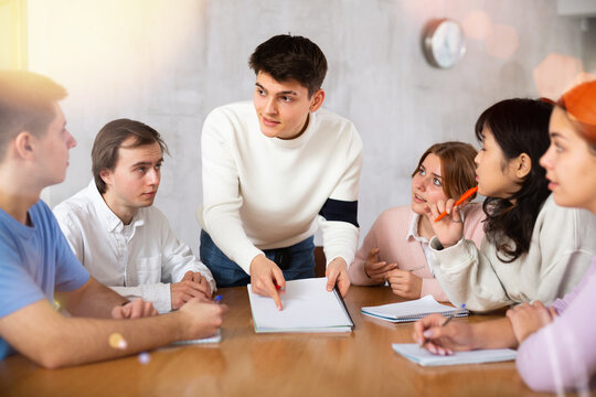 Young male tutor teaching group of students in college