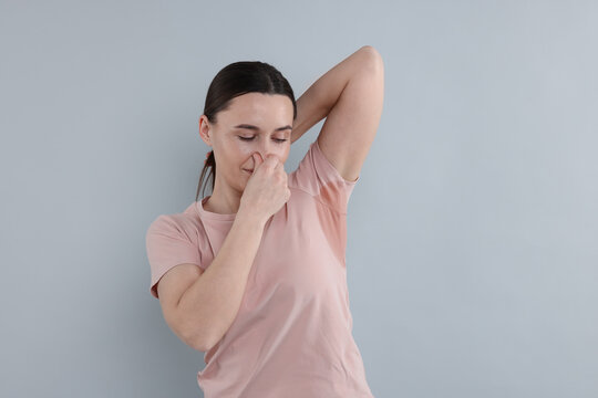 Woman with sweaty armpits on light grey background