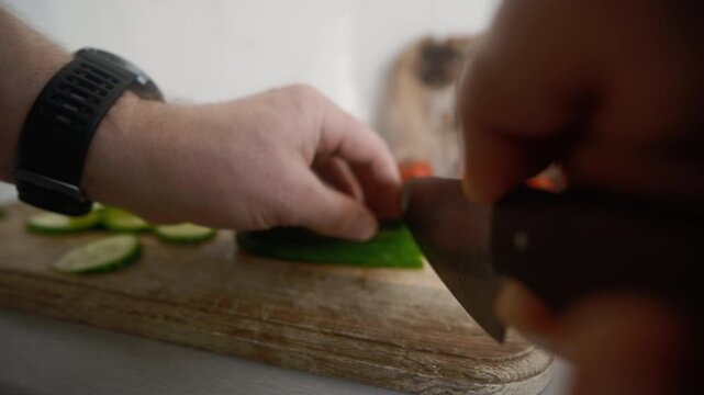 Man Slices Cucumbers On A Cutting Board In The Kitchen Using A Large Knife For A Salad, Object POV camera angle shot