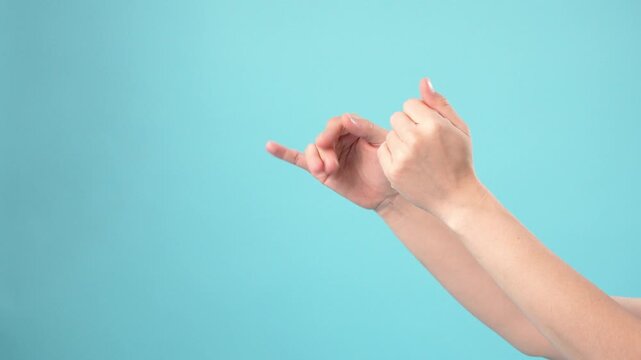 Hands showing shadow puppet bird shape on blue background
