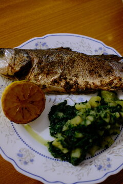 Adriatic sea bass brancin with Dalmatian-style potatoes and spinach stew, roasted lemon half