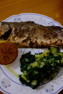 Adriatic sea bass brancin with Dalmatian-style potatoes and spinach stew, roasted lemon half