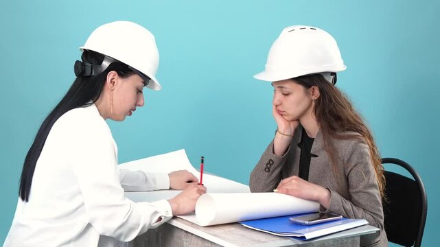 Two female architects studying blueprint and arguing in office