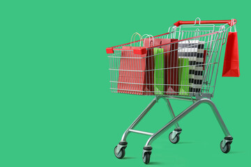 Shopping bags in cart on green background © Pixel-Shot
