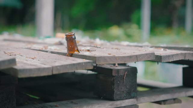 Parallax Orbit Shot: Broken Glass Bottle Neck on Abandoned Wooden Pallet Table | Shattered Brown Beer Bottle with Debris on Weathered Planks | Vandalism and Urban Decay Close-Up