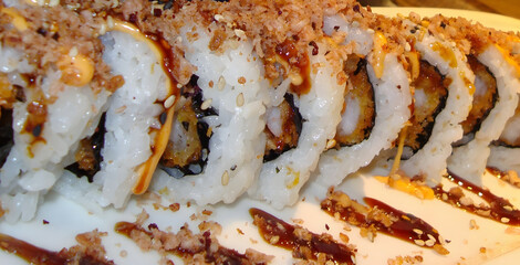 Close-up of crispy maki sushi roll topped with crunchy flakes and sweet teriyaki sauce © Jutamas
