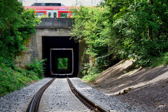 Symmetric view of the HGK (H&auml;fen und G&uuml;terverkehr K&ouml;ln) freight tracks in Cologne. A red regional train crosses on the bridge above. Industrial look