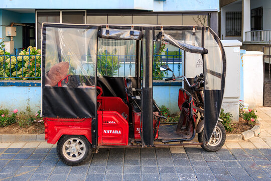 Red electric tuk-tuk parked on urban street. August 9, 2025, Mudanya Turkey