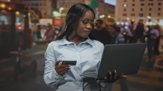 Woman holding laptop and creditcard, looking at screen with concerned expression on busy city street; concern security.