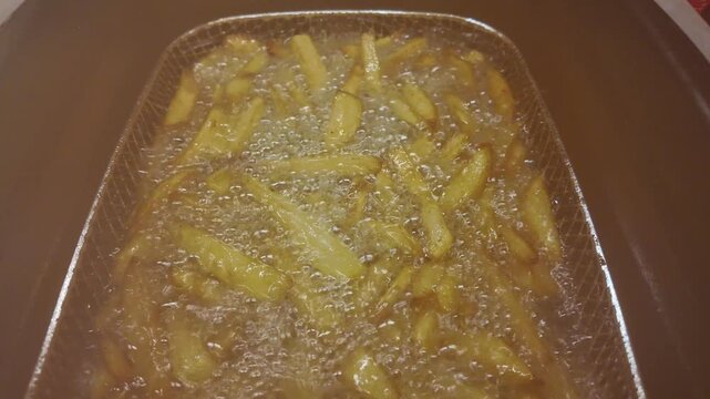 Crispy french fries cooking in deep fryer basket