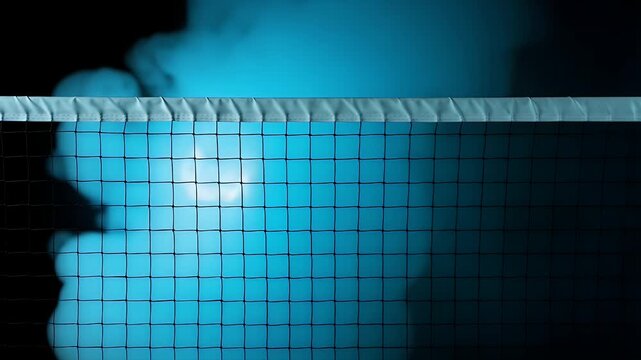 Close up view of a professional tennis net placed against a dark blue hazy background representing intensity and competitive spirit during a fast paced indoor night time game